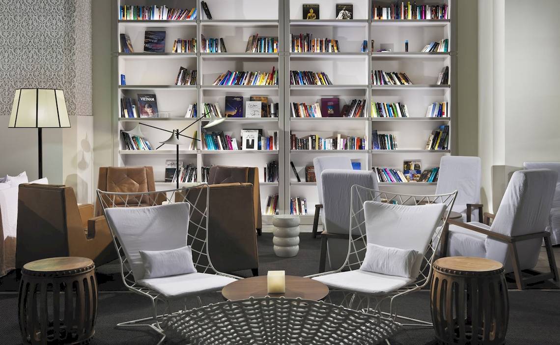 Loungebereich im H10 Timanfaya Palace Hotel mit Bücherregalen, Sesseln und Tischen.