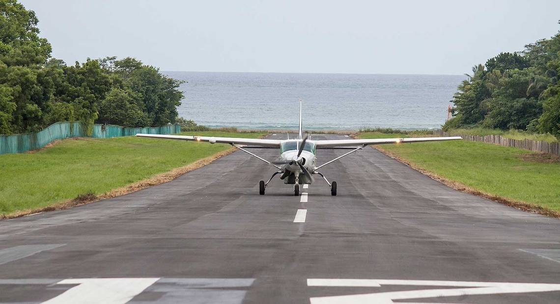 Ein Flugzeug auf dem Rollweg eines Flugplatzes mit dem Meer im Hintergrund.