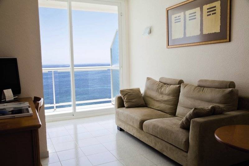 Wohnzimmer mit einem Sofa und einem großen Fenster, das auf das Meer hinausblickt.