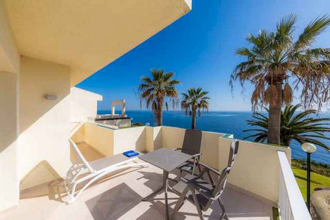 Balkon mit Blick auf das Meer im Blau Punta Reina Hotel mit Liegestuhl, Tisch und Stühlen.