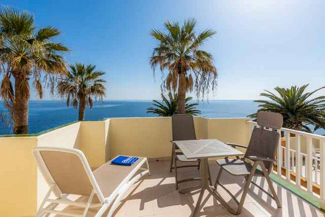 Hotelterrasse mit Blick auf den Ozean und Palmen