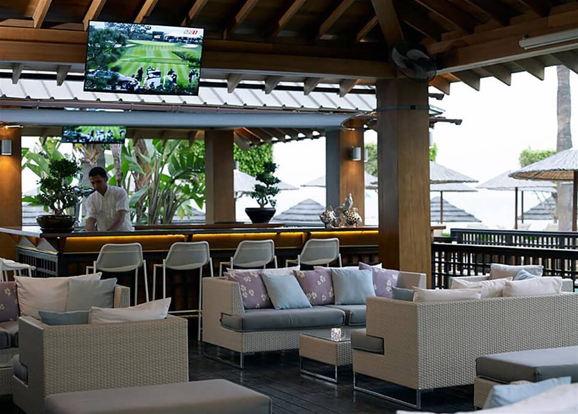 Innenansicht der Bar im Atlantica Miramare Beach Hotel mit Barkeeper und Sofas.