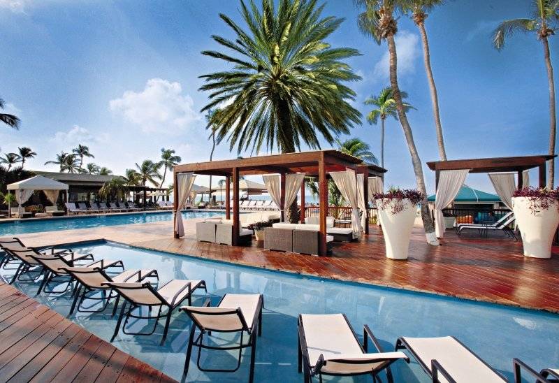 Außenpoolbereich mit Lounge-Bereich im Hotel Divi Tamarijn Aruba bei Sonnenschein