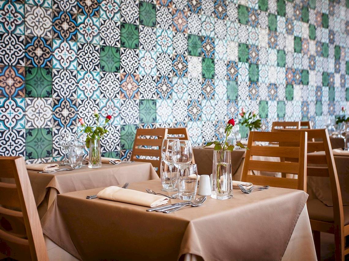 Restaurant-Innenbereich des Bianca Beach Resorts mit blau-grüner Wandfliesen und gedeckten Tischen.