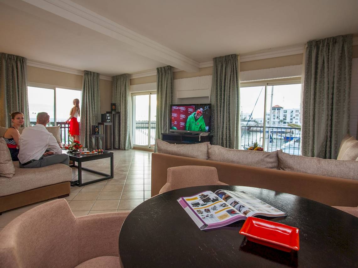 Hotel Wohnzimmer mit Fernseher, Sofas, Tisch und Aussicht auf den Hafen