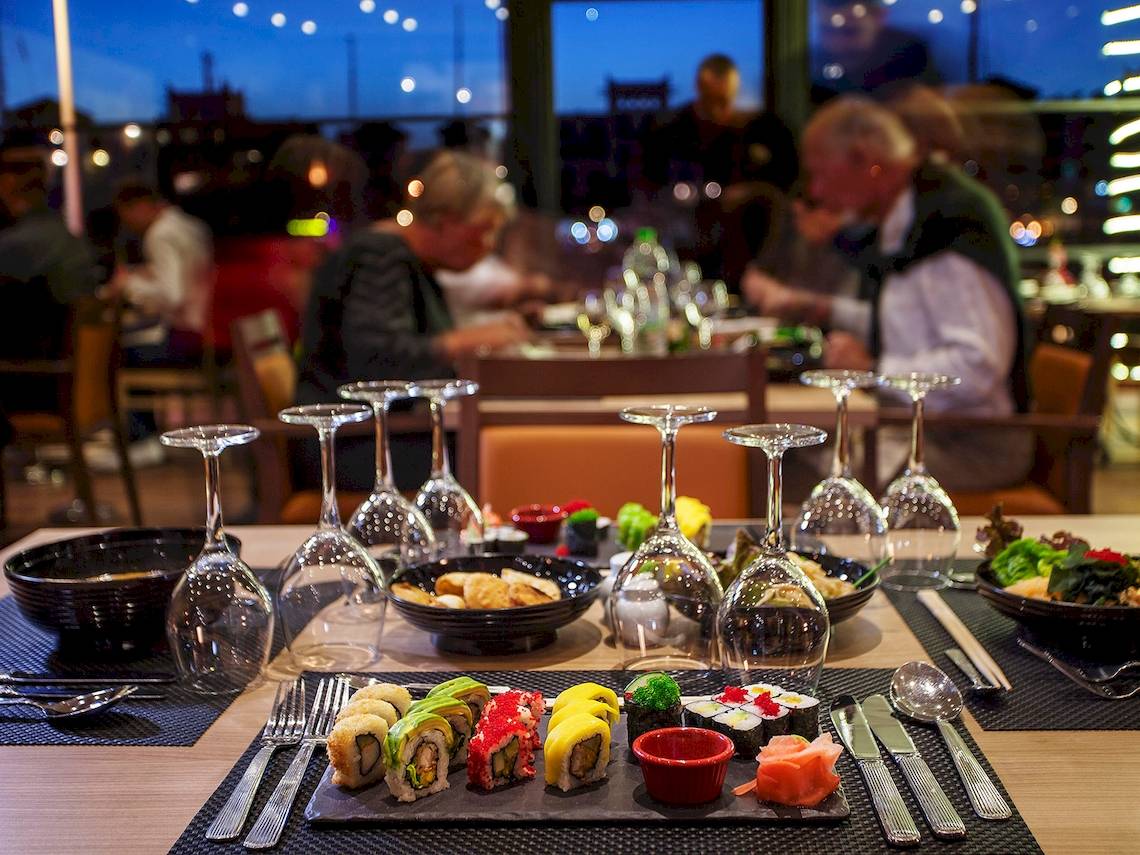 Restauranttisch im Bianca Beach Resort mit Sushi, Getränkegläsern und Geschirr.