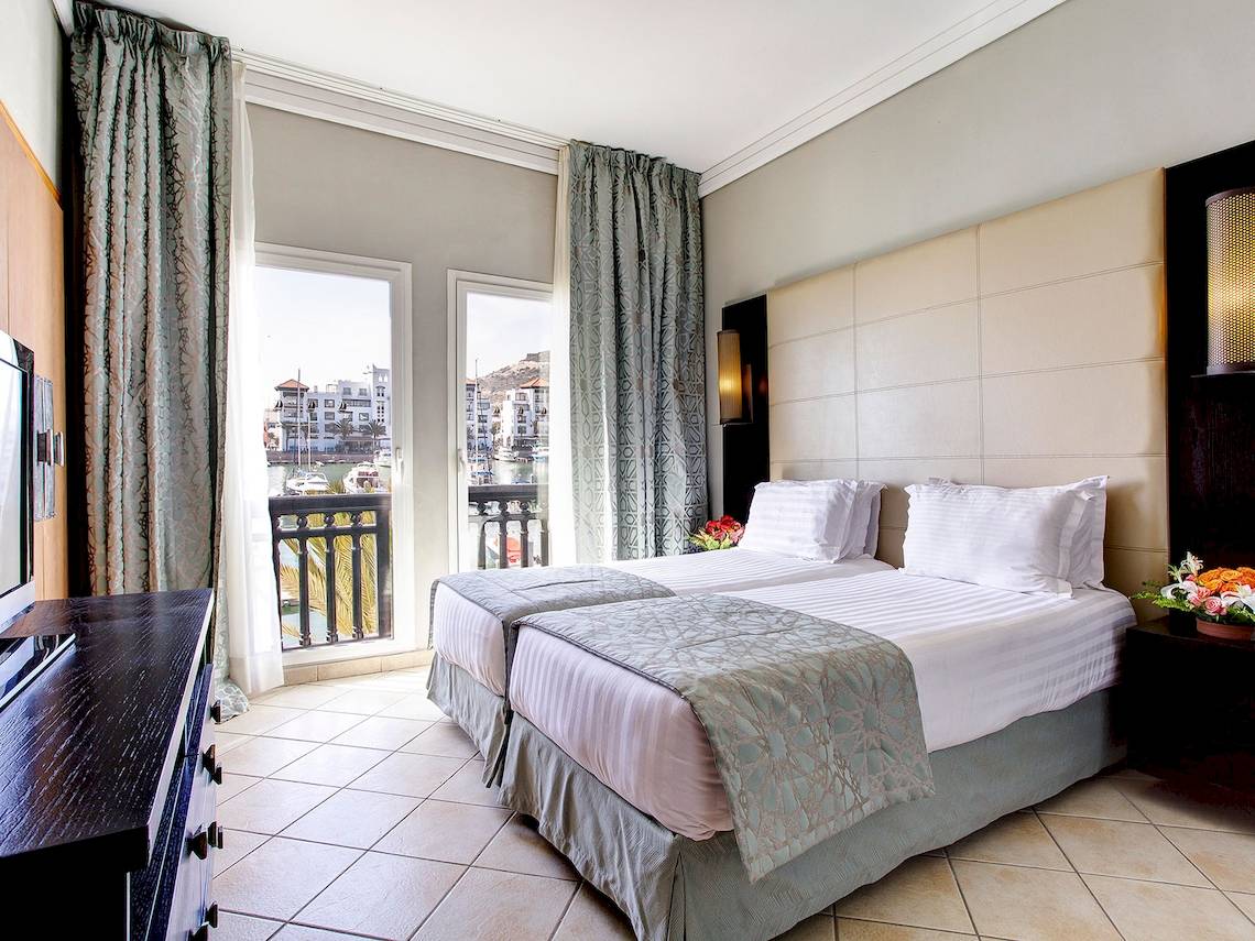 Doppelbettzimmer im Bianca Beach Resort mit Blick auf die Stadt und Balkon.