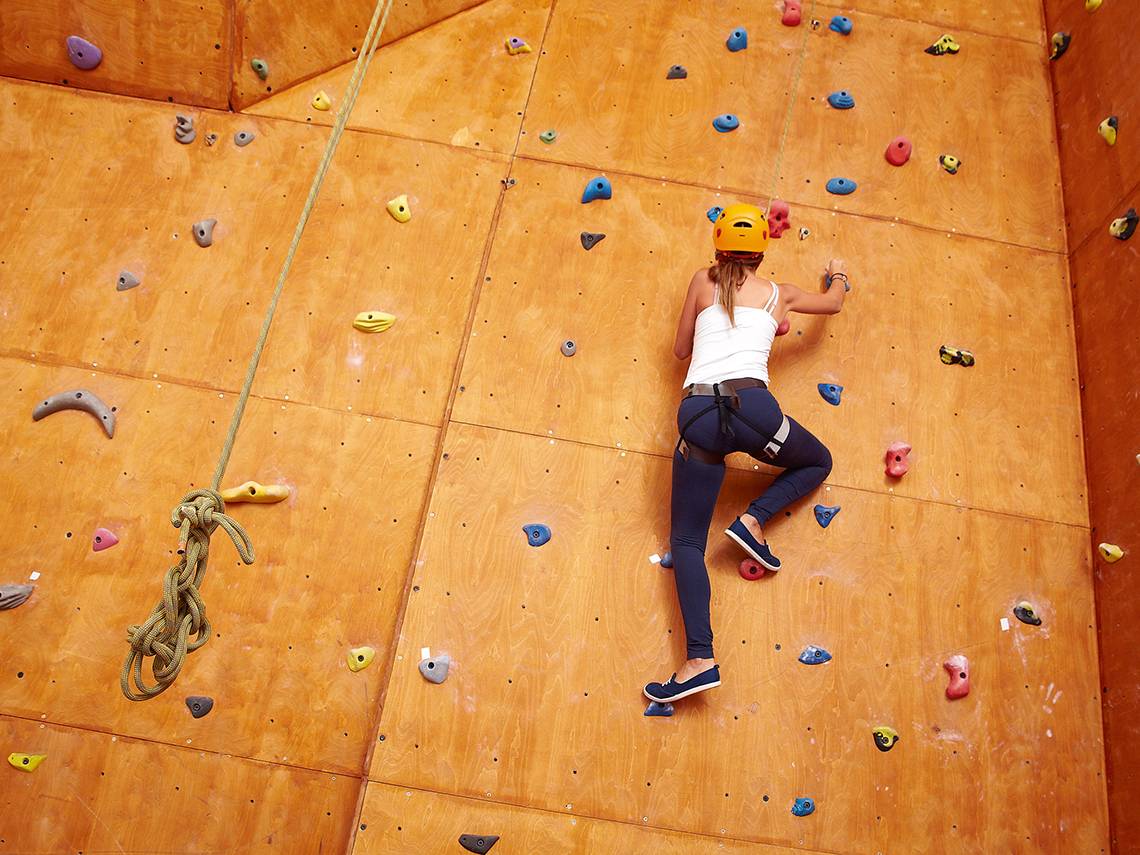 Eine Frau klettert an einer Wand im Indoor-Climbing-Center.