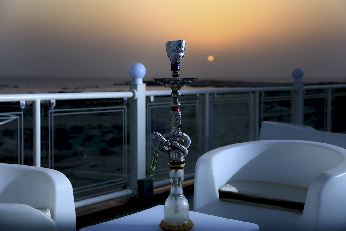 Sonnenuntergang auf dem Balkon des Wyndham Garden Salalah Mirbat mit einer Shisha auf einem Tisch.