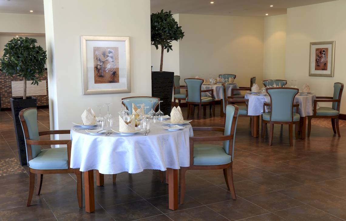 Wyndham Garden Salalah Mirbat Speisesaal mit Tisch und Stühlen, Pflanzen und Gemälden an den Wänden