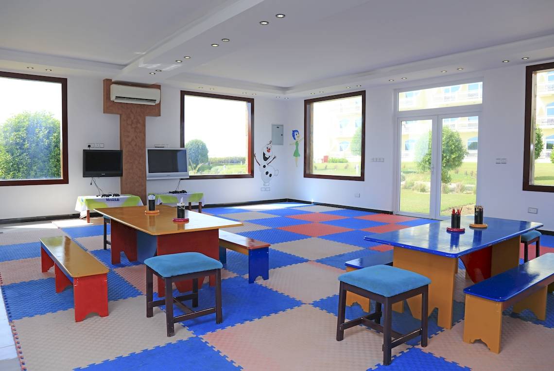 Spielzimmer im Wyndham Garden Salalah Mirbat mit bunten Teppichfliesen, Tischen und Stühlen.