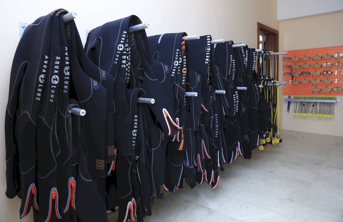 Reihe von schwarzen Aqua-Lung-Tauchanzügen an der Wand im Wyndham Garden Salalah Mirbat Hotel.