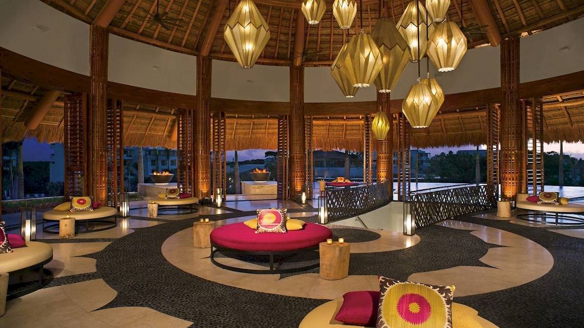 Innenraum des Hotel-Lobby-Bereichs von Secrets Akumal Riviera Maya mit Loungemöbeln, Beleuchtung und Aussicht.