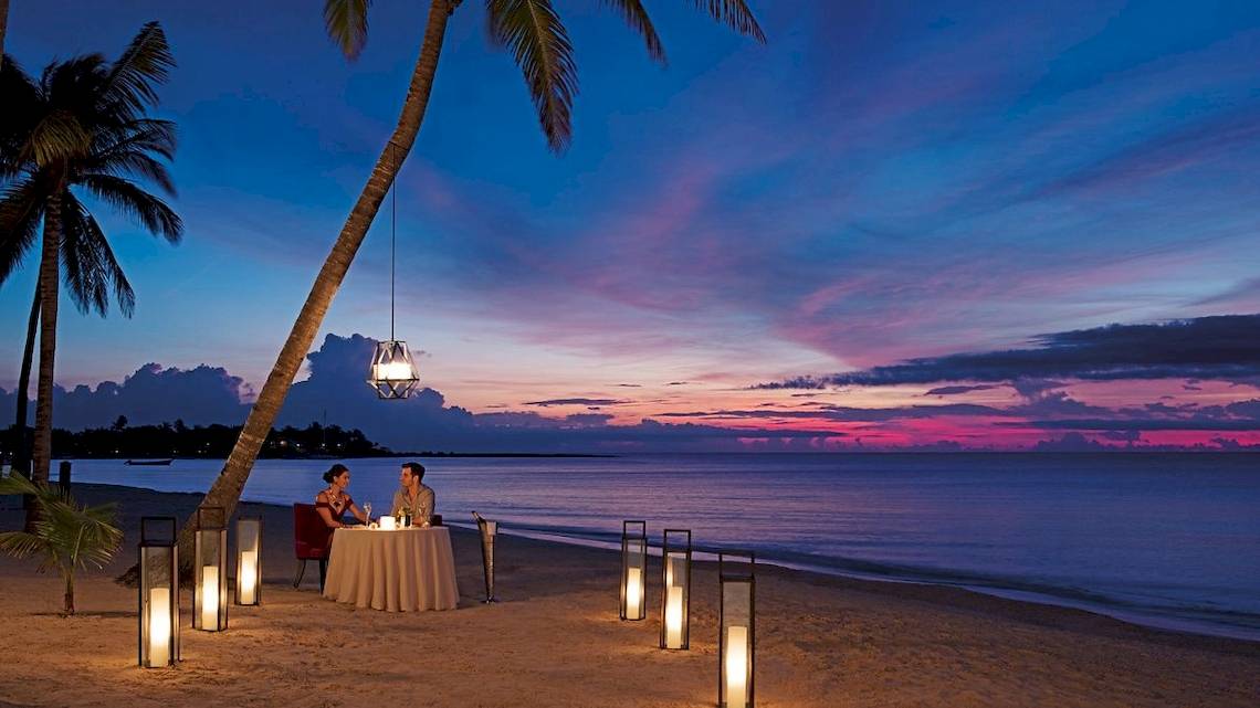 Paar genießt ein Abendessen am Strand im Secrets Akumal Riviera Maya.