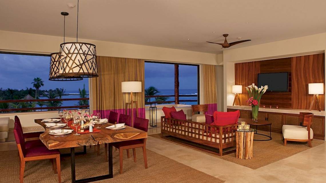 Wohnzimmer im Secrets Akumal Riviera Maya mit Blick auf das Meer, Tisch und Sofa.