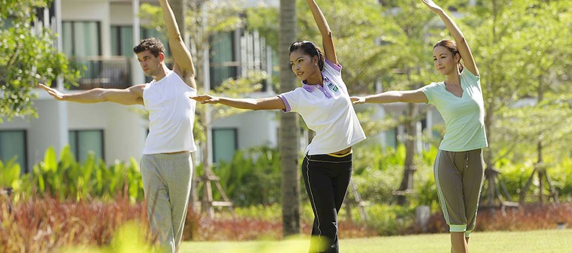 Gäste im Holiday Inn Mai Khao Resort bei Yoga-Übungen im Freien.