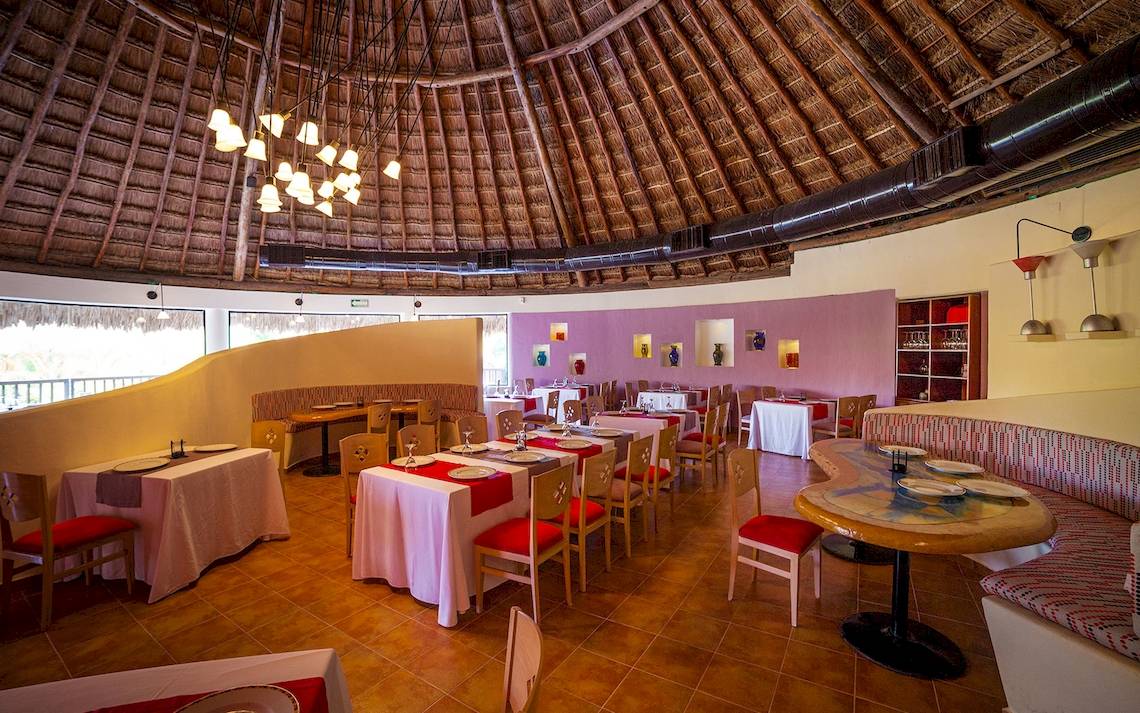Speisesaal im Hotel The Reef Coco Beach mit runden Tischen und roten Stühlen.