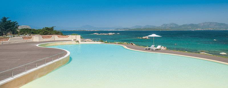 Außenpool des Cala Cuncheddi Hotels mit Blick auf das Meer und Berge.