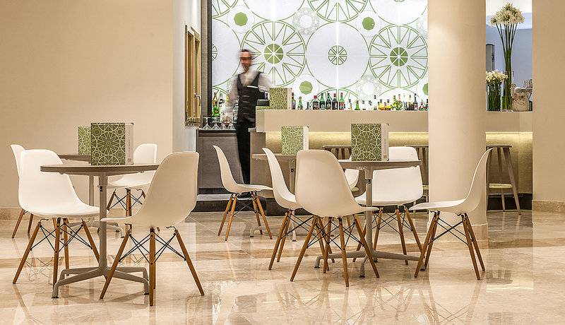 Cala Cuncheddi Hotellounge mit weißen Stühlen und runden grünen Wandmustern