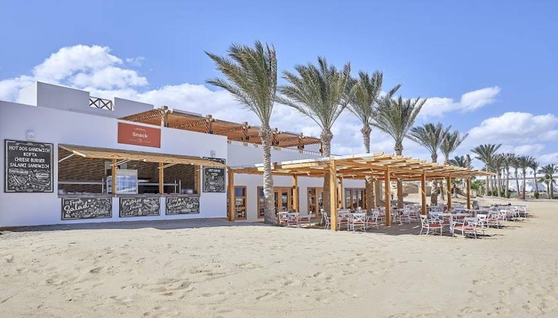 Strandrestaurant des JAZ Neo Reef Marsa Alam Hotels mit Palmen und Tischen im Freien