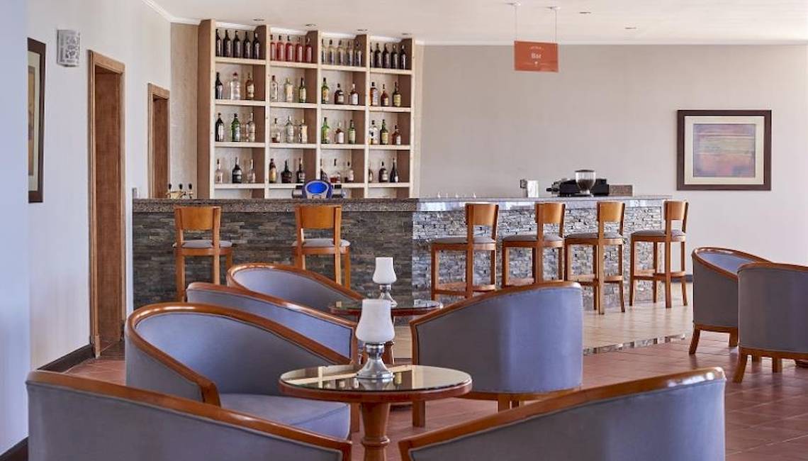 Barbereich im JAZ Neo Reef Marsa Hotel mit Barhockern und Getränken.