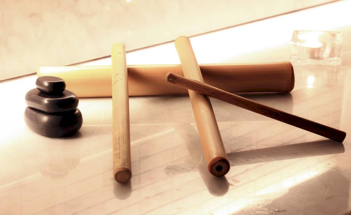 Ein Foto von drei Bambusstäben und zwei Steinen auf einer Marmorplatte.