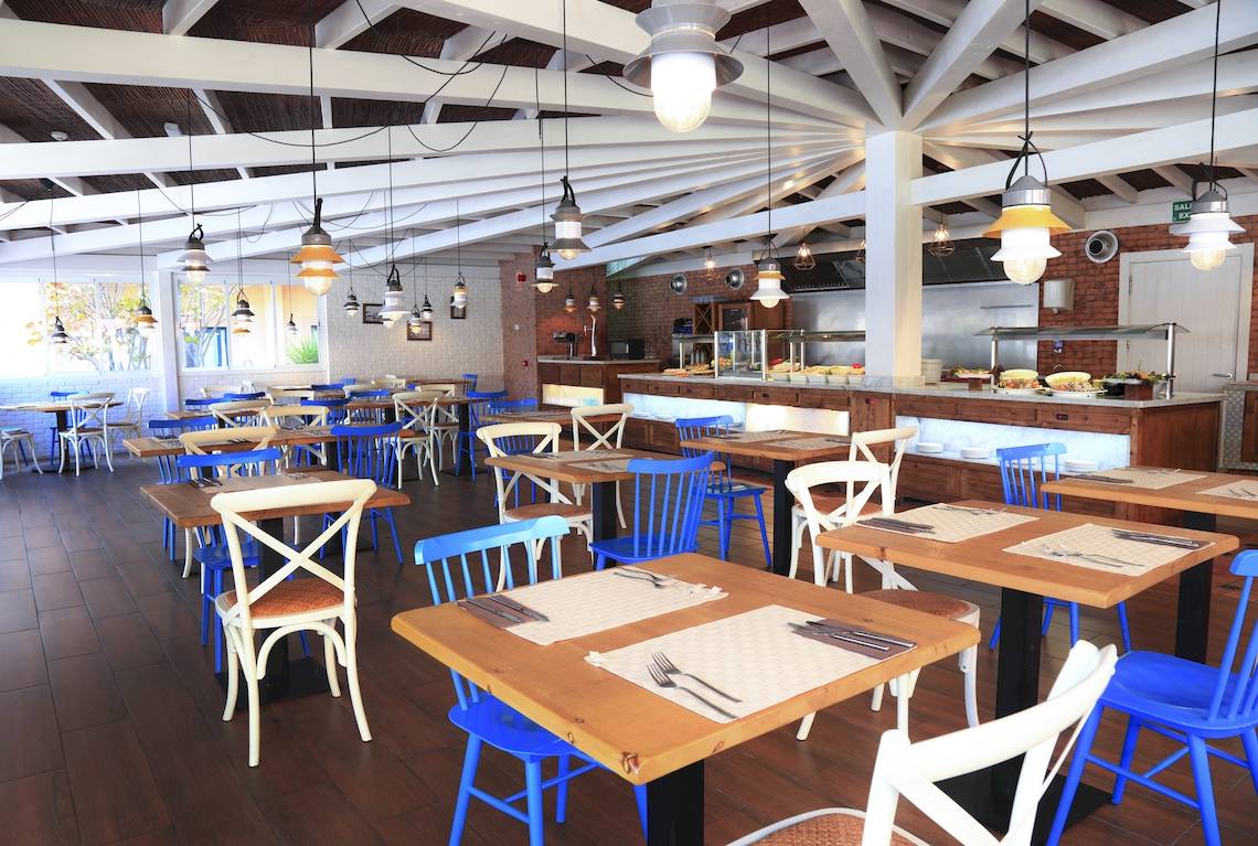 Innenansicht des Restaurants im O7 Aloe Corralejo Hotel mit blauen Stühlen und Holztischen.