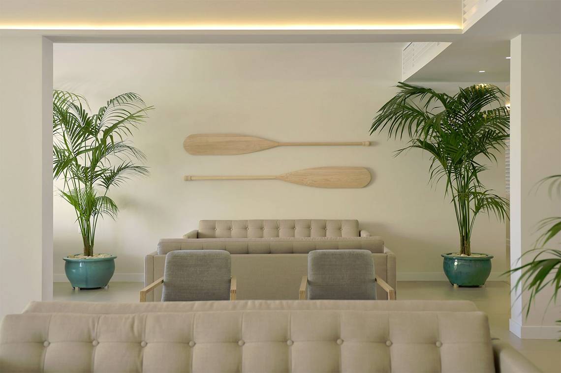 Wohnzimmer mit Sofas, Palmen und Rudern an der Wand im Sunrise Gardens Hotel.