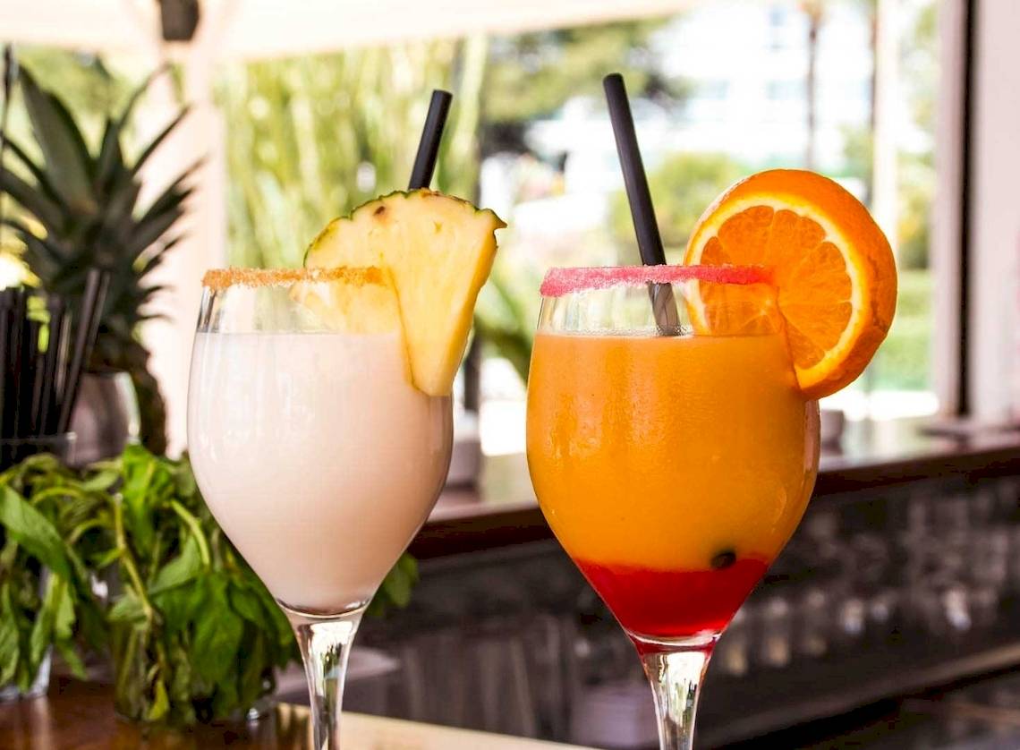 Zwei Cocktails auf einer Bar im Hotel Torre del Mar, mit Früchten und Strohhalmen.