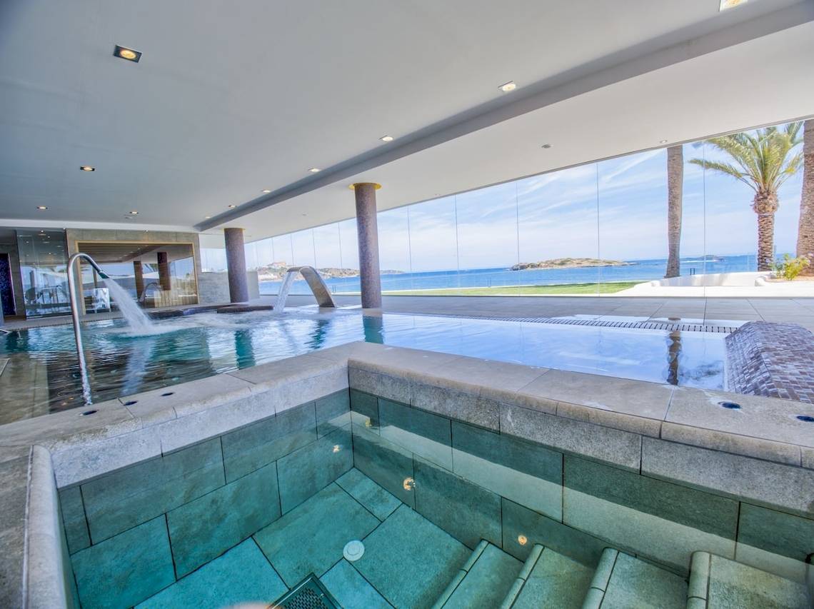 Innenpool des Torre del Mar Hotels mit Meerblick und Palmen im Hintergrund.