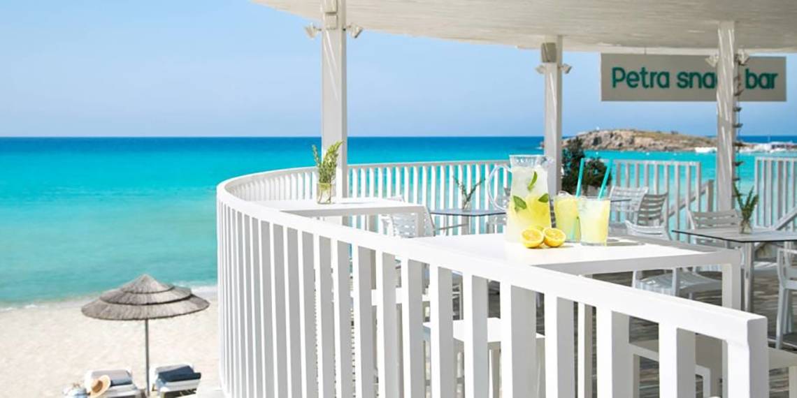 Außenterrasse des Nissi Beach Resorts mit Blick auf das Meer und einem Glas Limonade