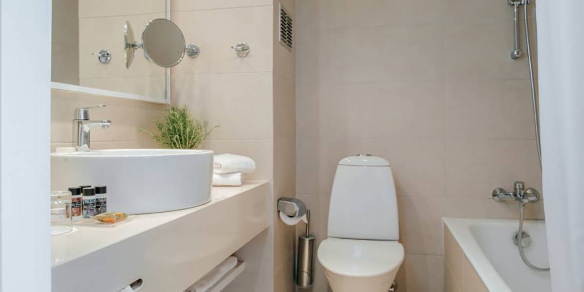 Badezimmer im Nissi Beach Resort mit weißem Waschbecken, Toilette und Badewanne.