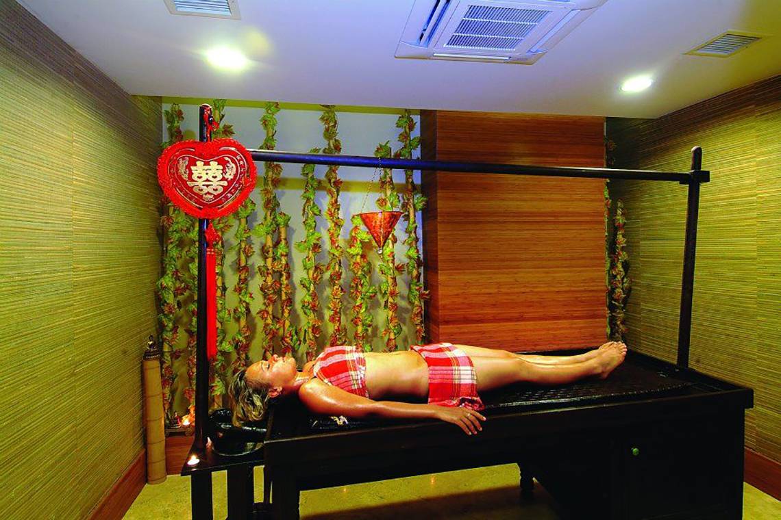 Eine Frau liegt auf einer schwarzen Massageliege im Spa-Bereich des Royal Dragon Hotels.