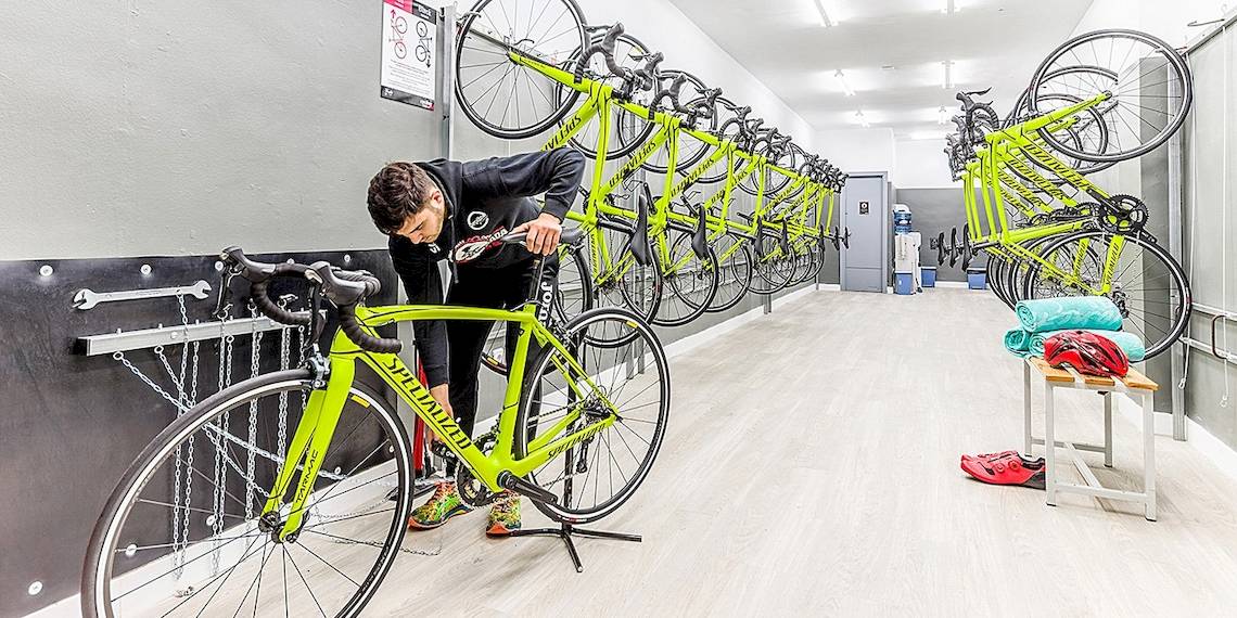 Mann, der ein Fahrrad in einer Fahrradwerkstatt des Viva Golf Adults Only Hotels repariert