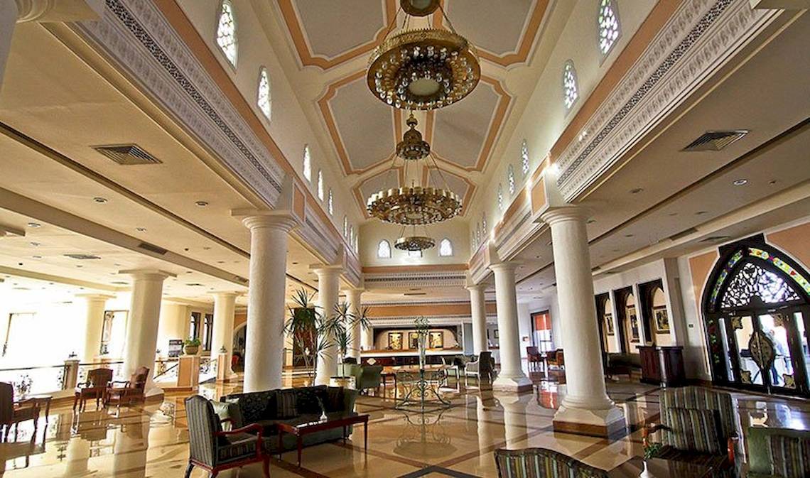 Lobby des Charmillion Club Resorts mit hohen Säulen, Kronleuchtern und Möbeln.