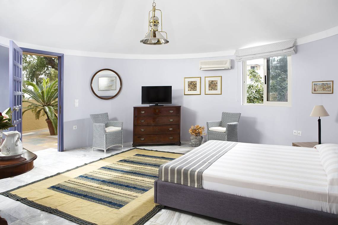Schlafzimmer im Dionysos Hotel mit einem Bett, zwei Stühlen, einem Tisch und einem Fernseher