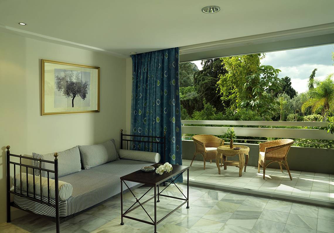 Der Balkon des Dionysos Hotels mit einer Couch, einem Tisch und zwei Stühlen, Blick auf die Natur