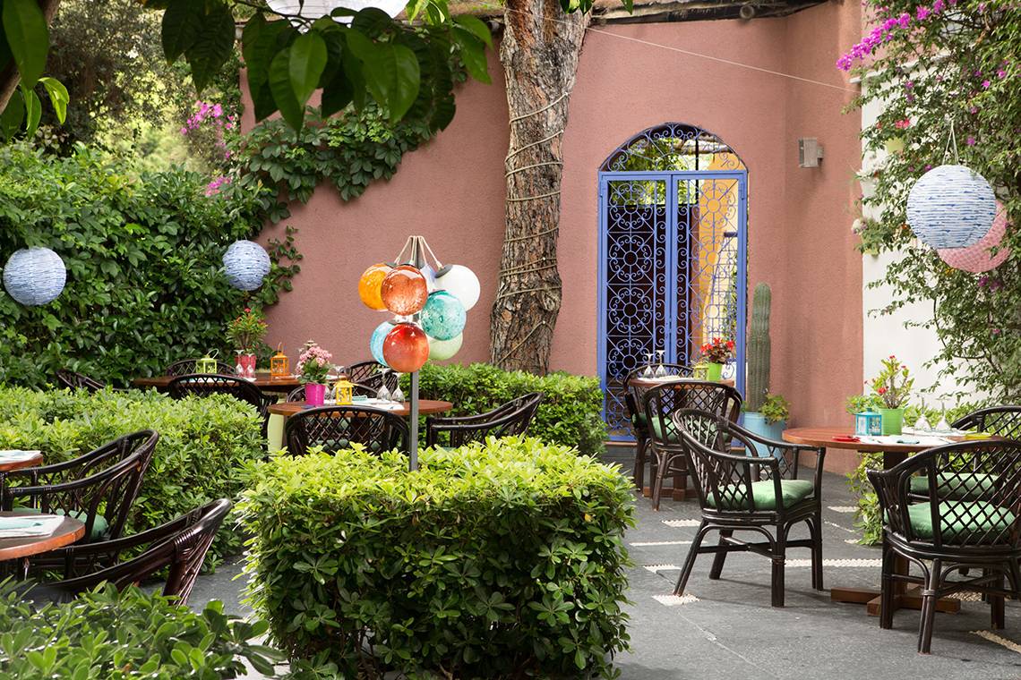 Gartenterrasse des Dionysos Hotels mit bunten Dekorationen und begrünten Bereichen.