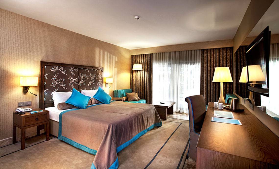 Ein elegantes Hotelzimmer im Marti Myra Hotel mit Doppelbett, Nachttischen, Schreibtisch und Fernseher.