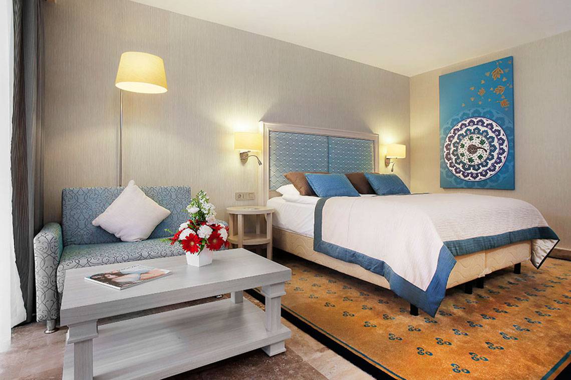 Schlafzimmer im Marti Myra Hotel mit einem Bett, einem Sofa, einem Tisch und einer Lampe.