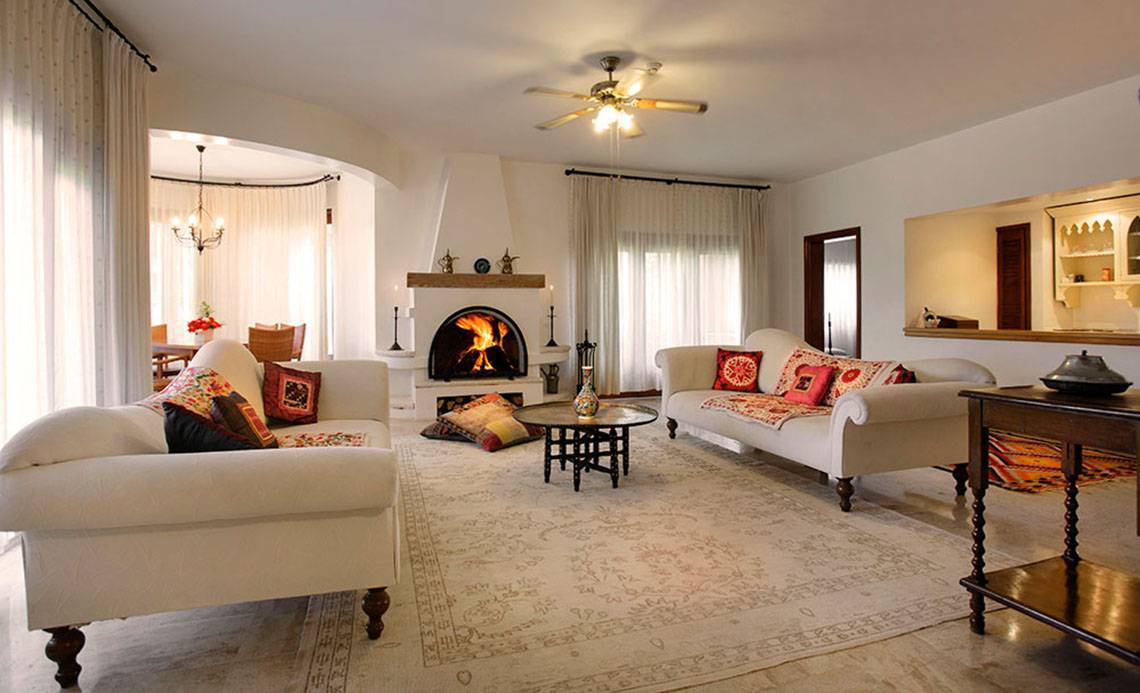 Wohnzimmer im Marti Myra Hotel mit zwei weißen Sofas, einem Kamin und einem Teppich.