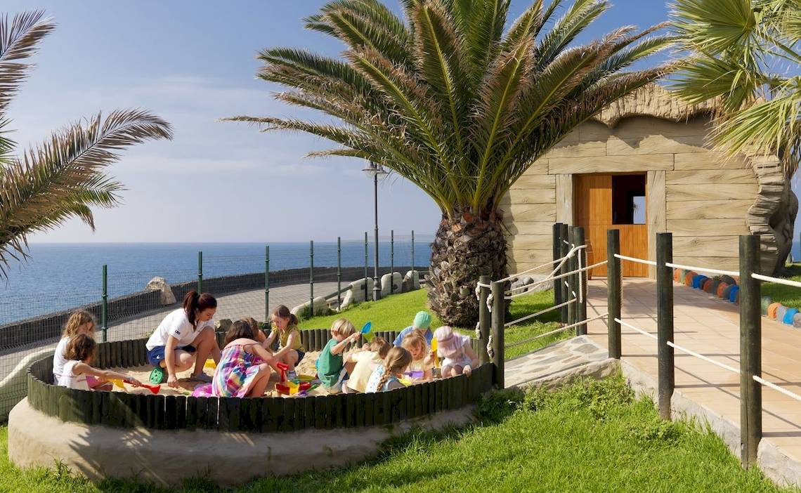Gruppe von Kindern spielt im Sandkasten am Strand vor dem H10 Rubicon Palace