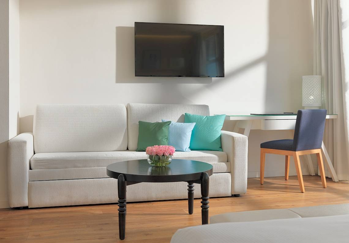 Wohnzimmer im H10 Rubicon Palace mit Sofa, Tisch, Fernseher und Stuhl.