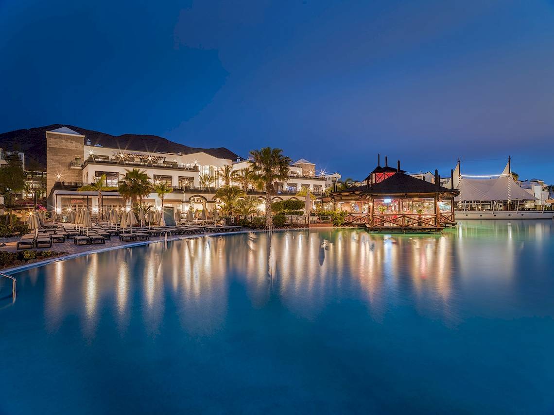 Nachtansicht des H10 Rubicon Palace mit Swimmingpool, Loungebereich und Beleuchtung.