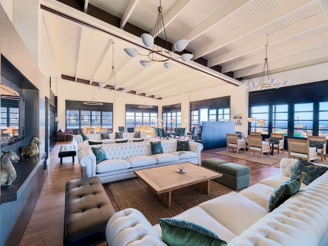 Lobby des H10 Rubicon Palace mit weißen Sofas, Holztischen und Panoramafenstern.