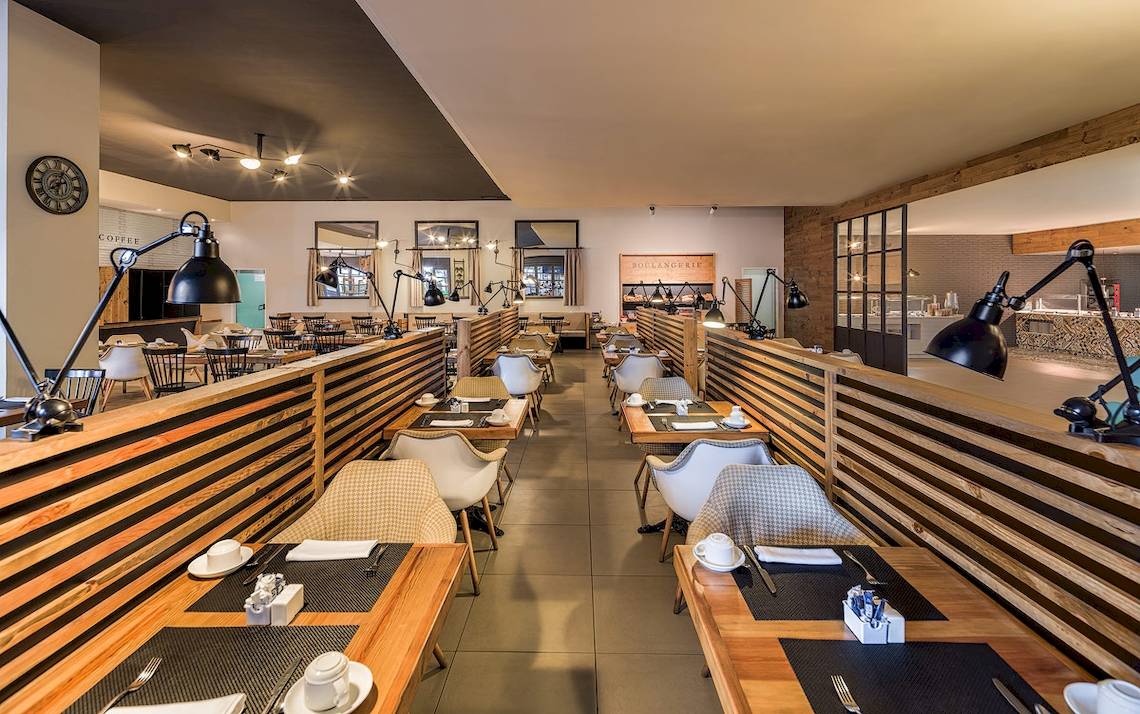 Innenansicht des Restaurants im H10 Rubicon Palace Hotel mit modernen Holztischen und Stühlen.