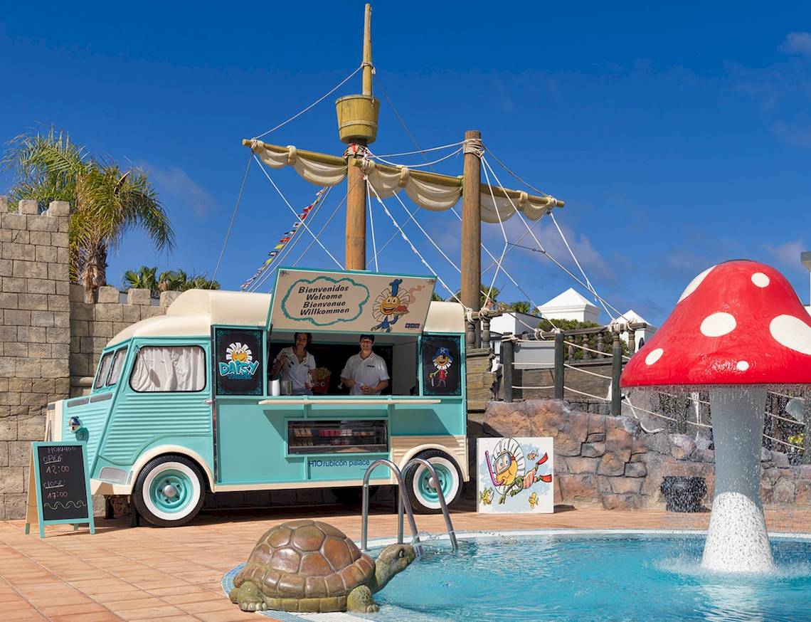 Eiswagen von H10 Rubicon Palace neben einem Pool mit einer riesigen roten Pilzskulptur.