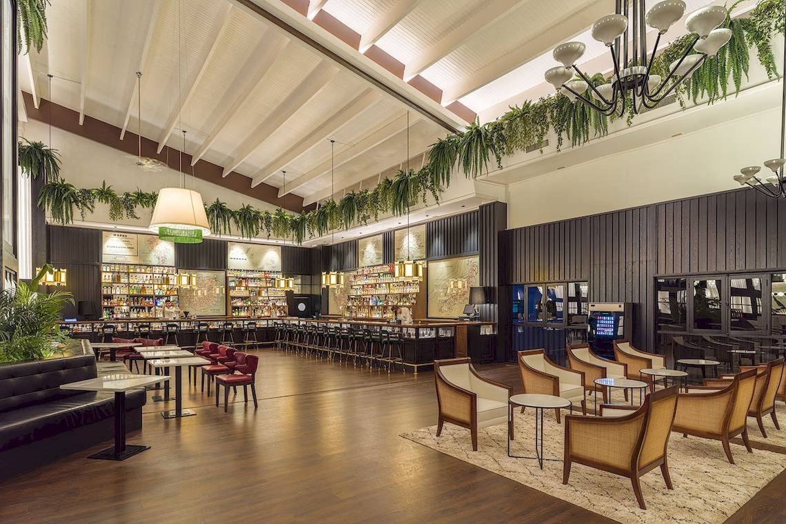 Innenbereich der Bar im H10 Rubicon Palace Hotel mit Holzboden, Möbeln und Pflanzen.