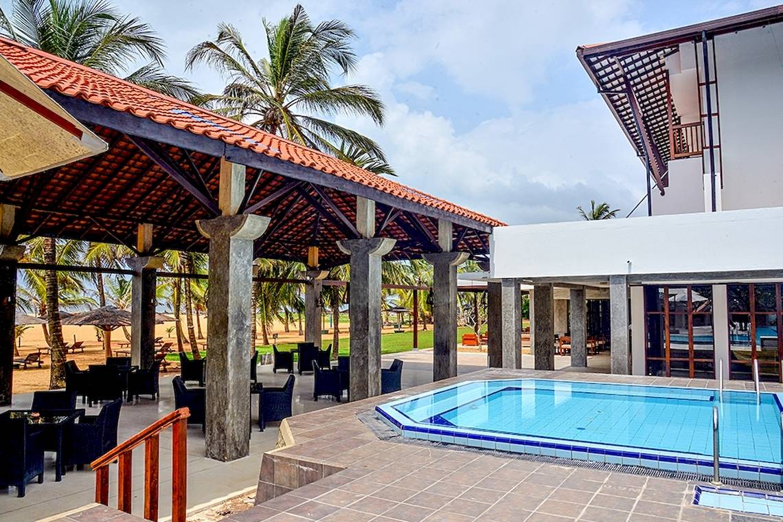 Pool-Terrasse des Goldi Sands Hotels mit blauem Wasser und umgeben von Palmen.