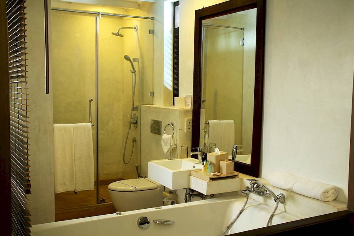Badezimmer des Goldi Sands Hotels mit Badewanne, Dusche, Spiegel und Toilette.